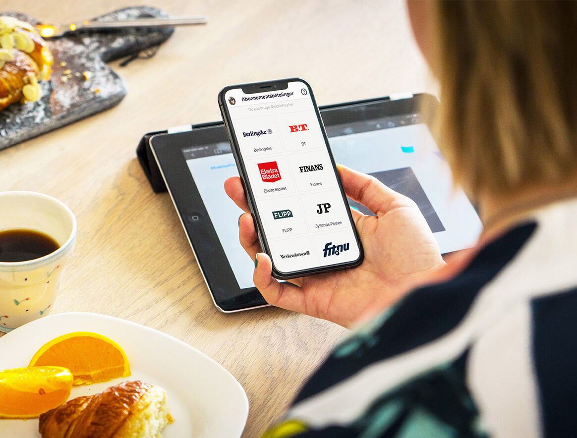 Billede af kvinde, der kigger ind i, hvilke betalingsaftaler hun kan tilmelde sig med MobilePay Subscriptions.