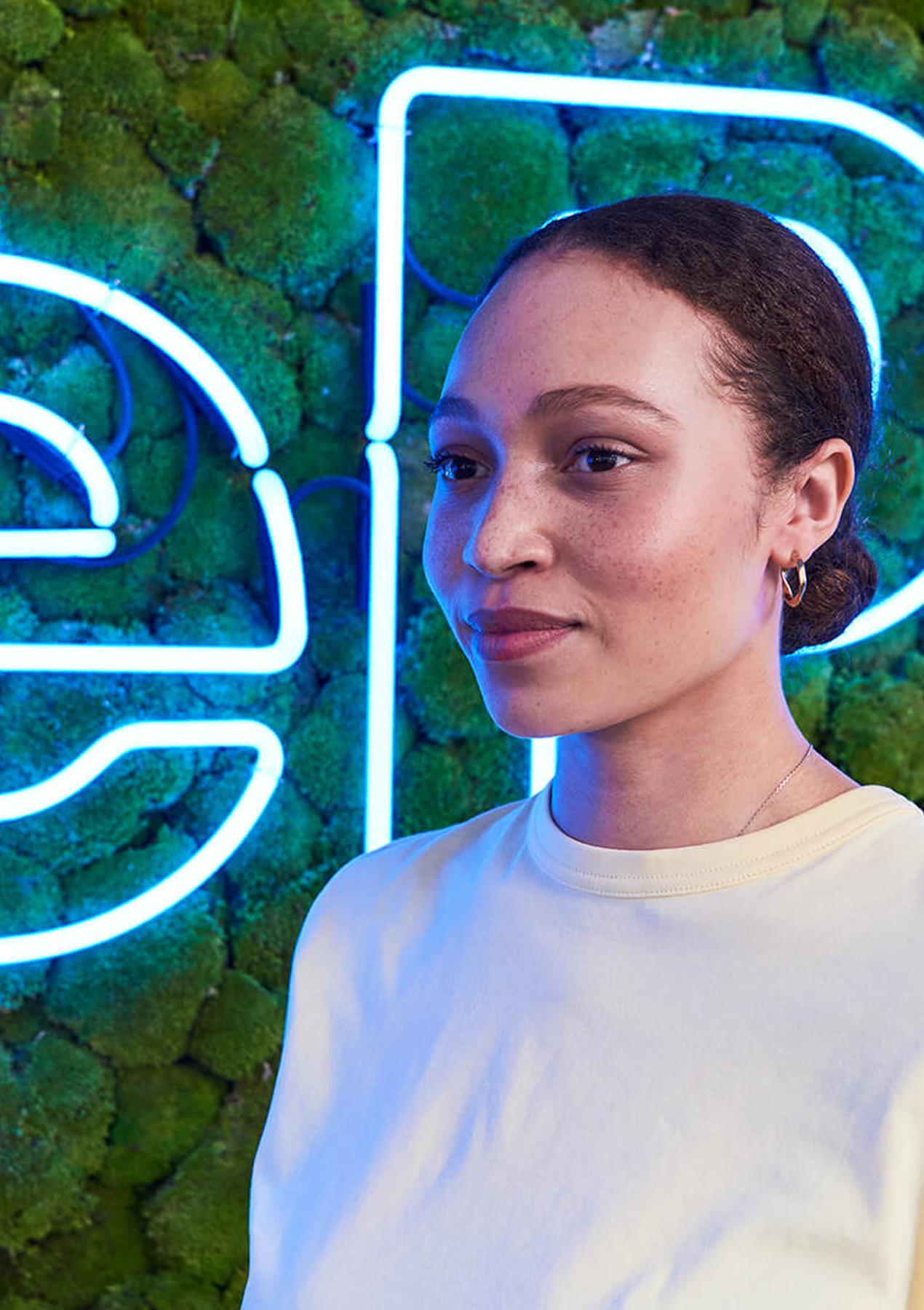 Portrait of a girl standing in front of a green MobilePay wall.