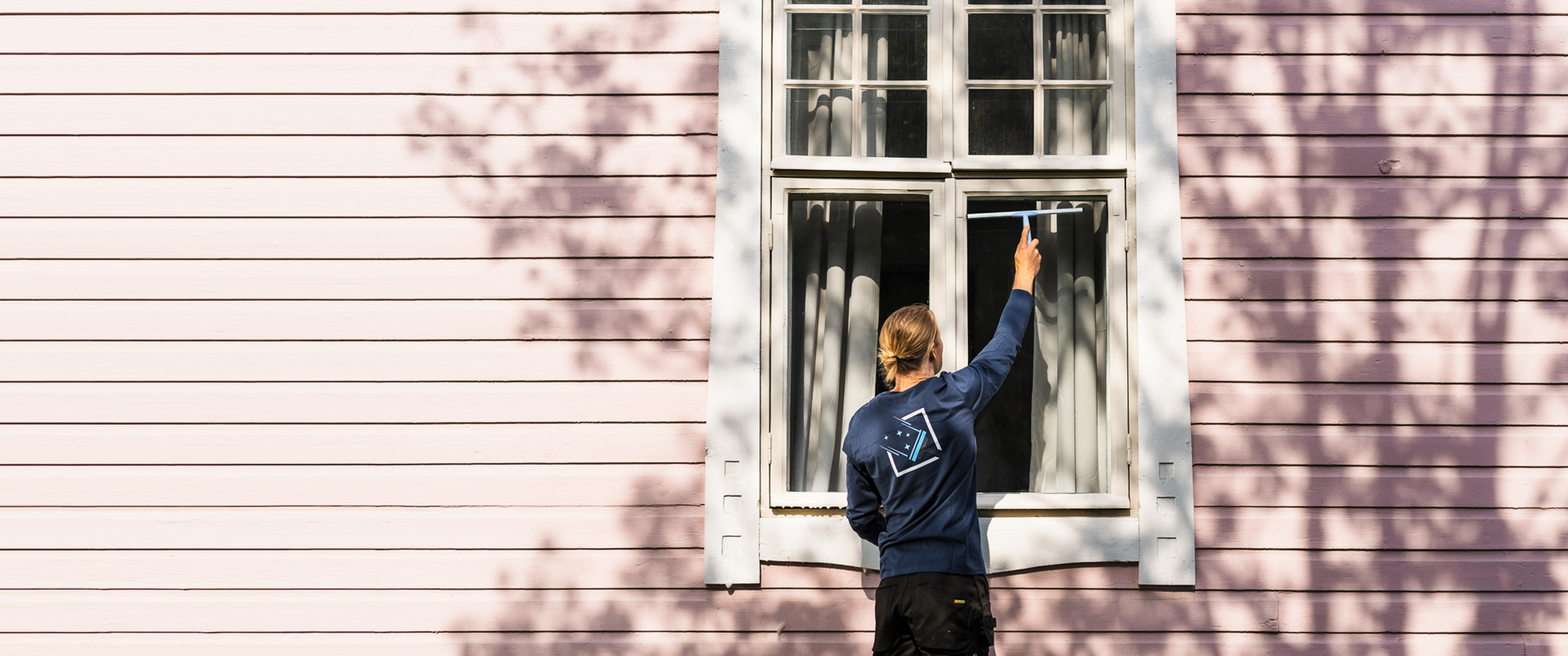 Man cleaning windows outside a pink house.
