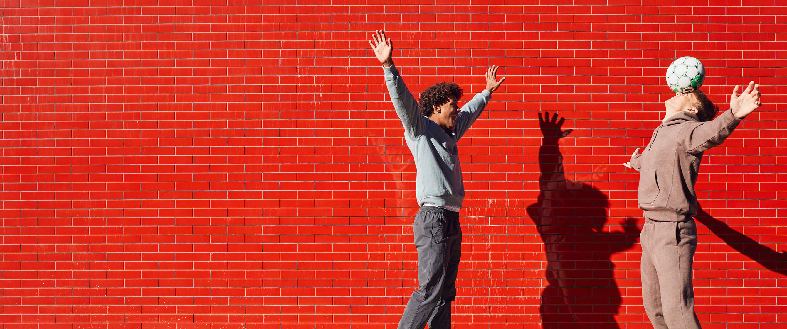 Boy playing soccer in front of a red wall.