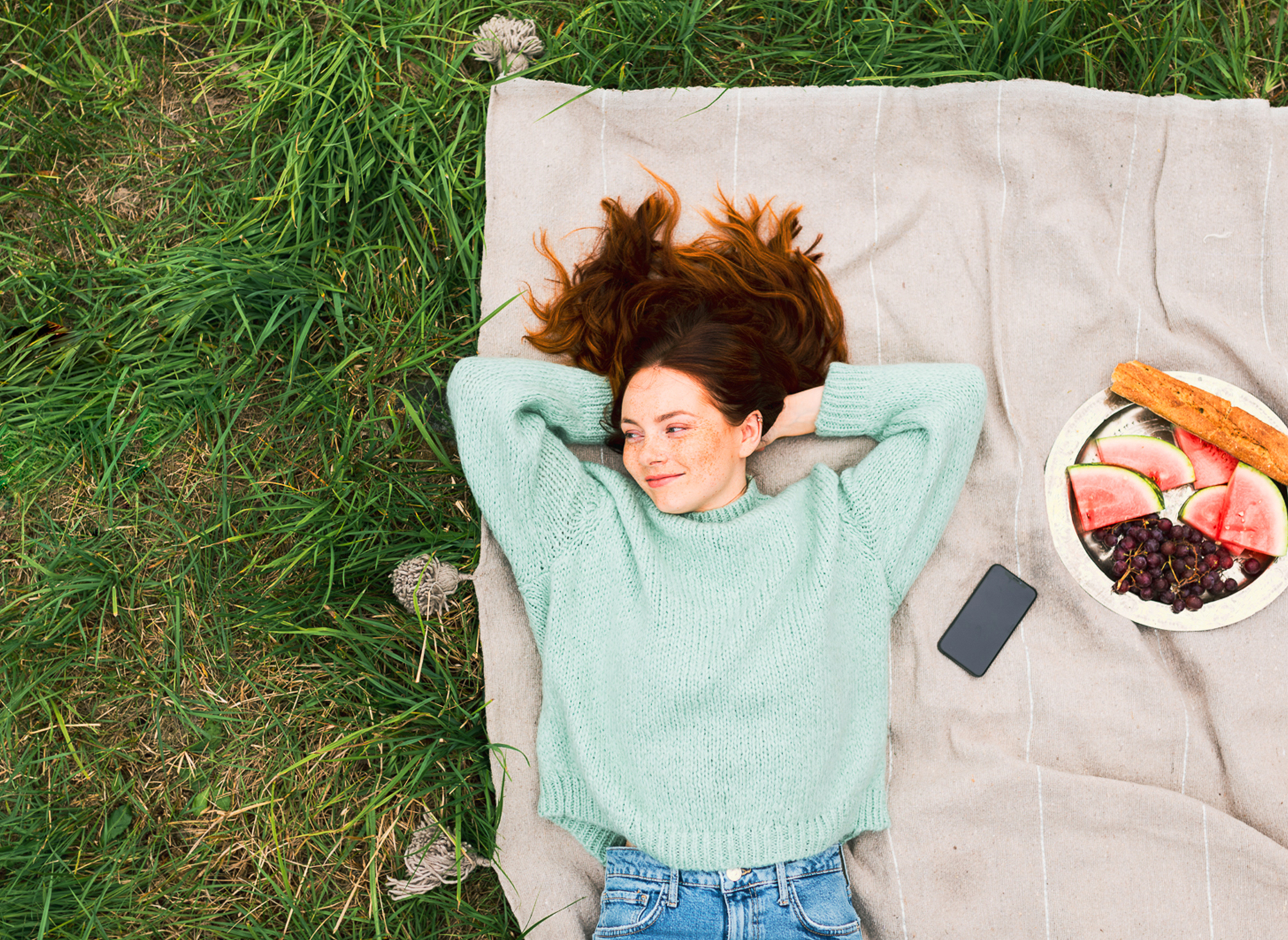 Girl in a park relaxing on a blanket.