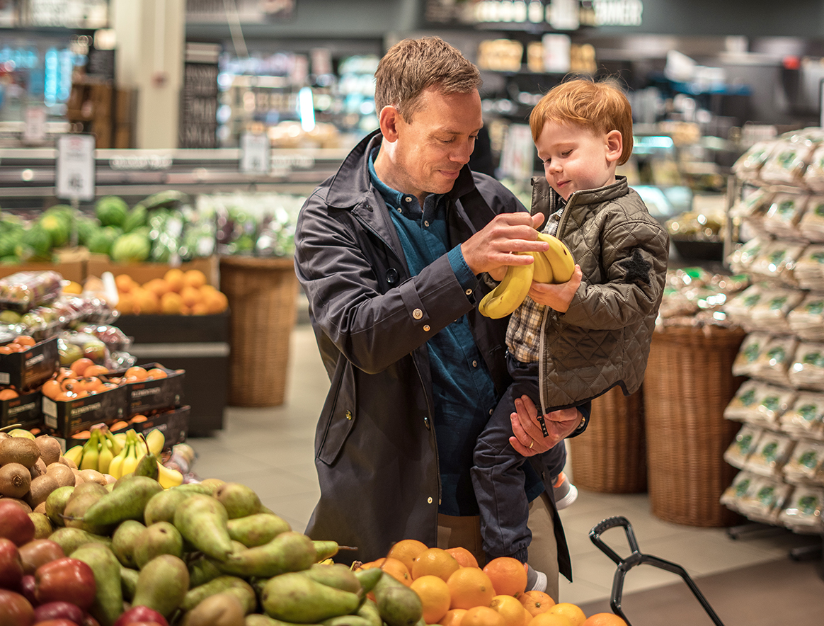 Dad and his child in a supermarket, paying in the store with MobilePay