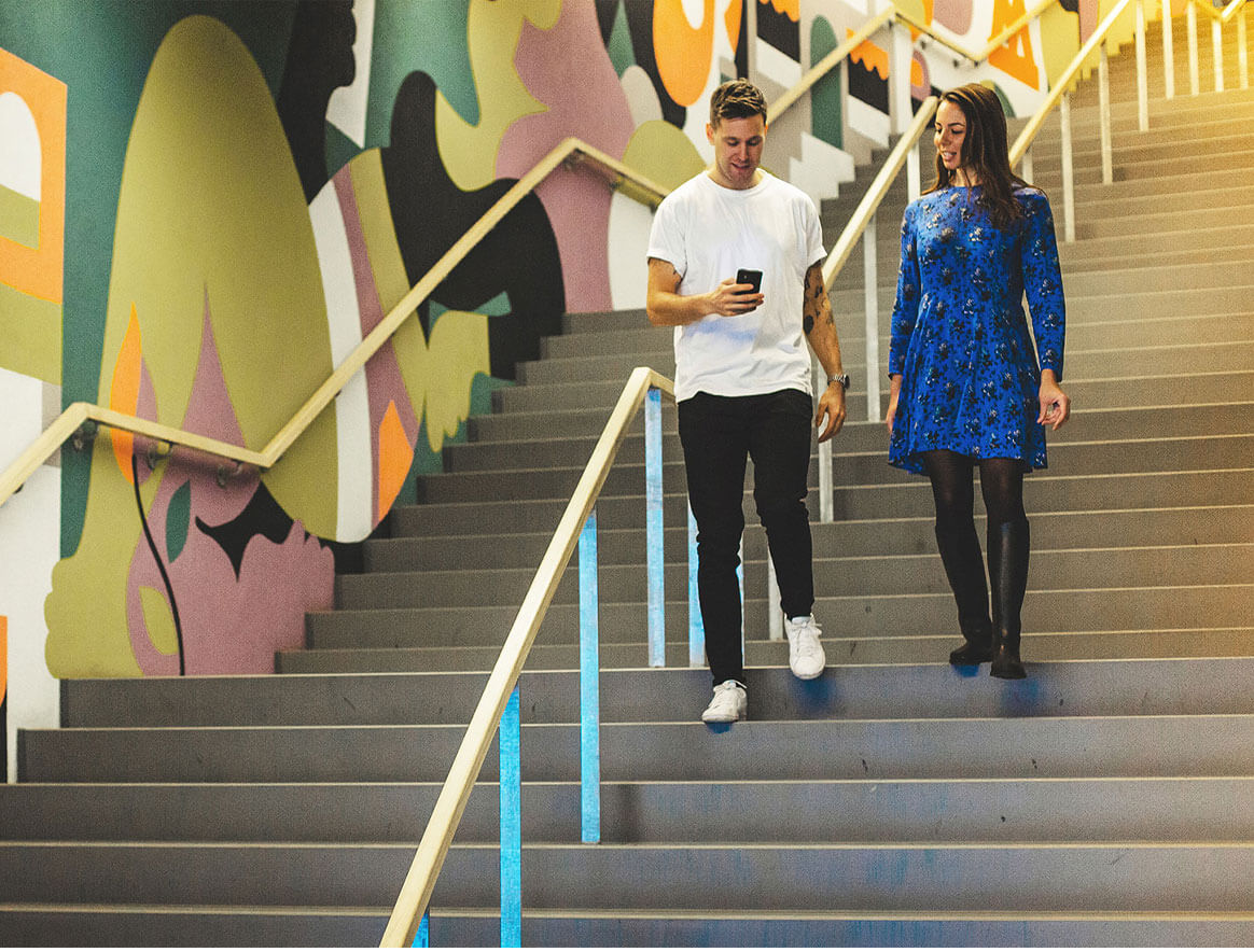Two people walking on a stair and paying with MobilePay.